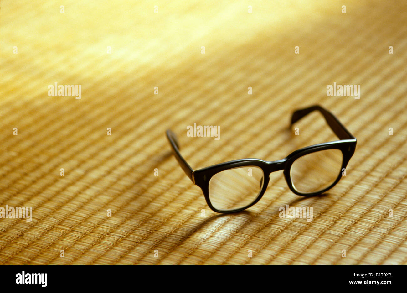 Thick old black glasses on tatami with window light. Stock Photo