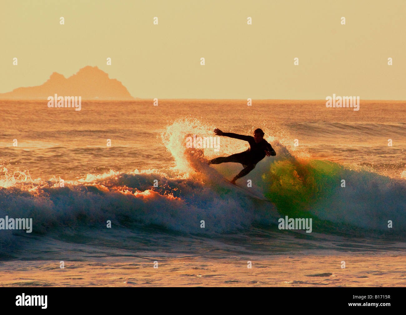 Surfing as the sun sets at Sennen in Cornwall. Stock Photo