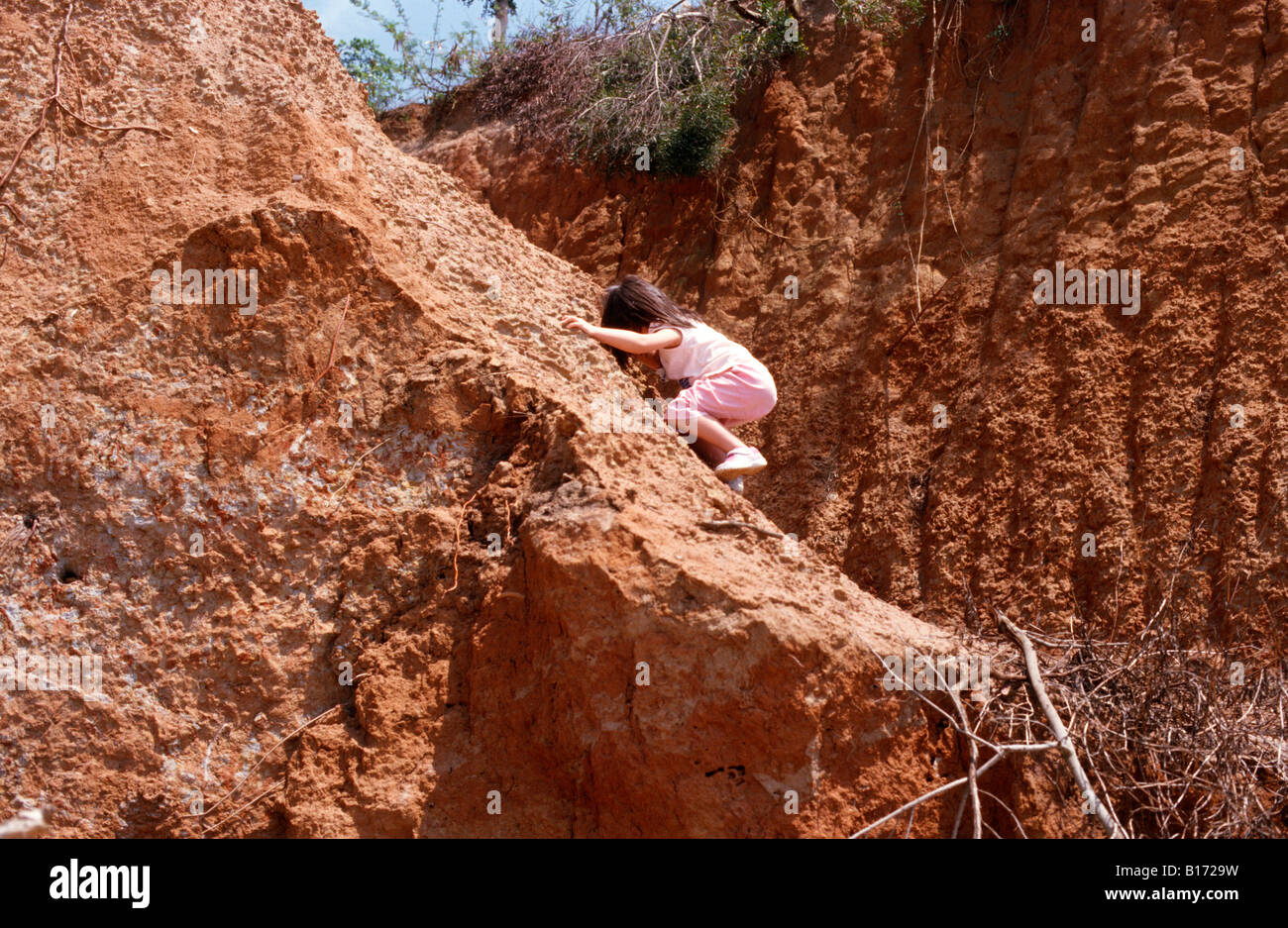 Four year old girl climbing down a hill. Stock Photo