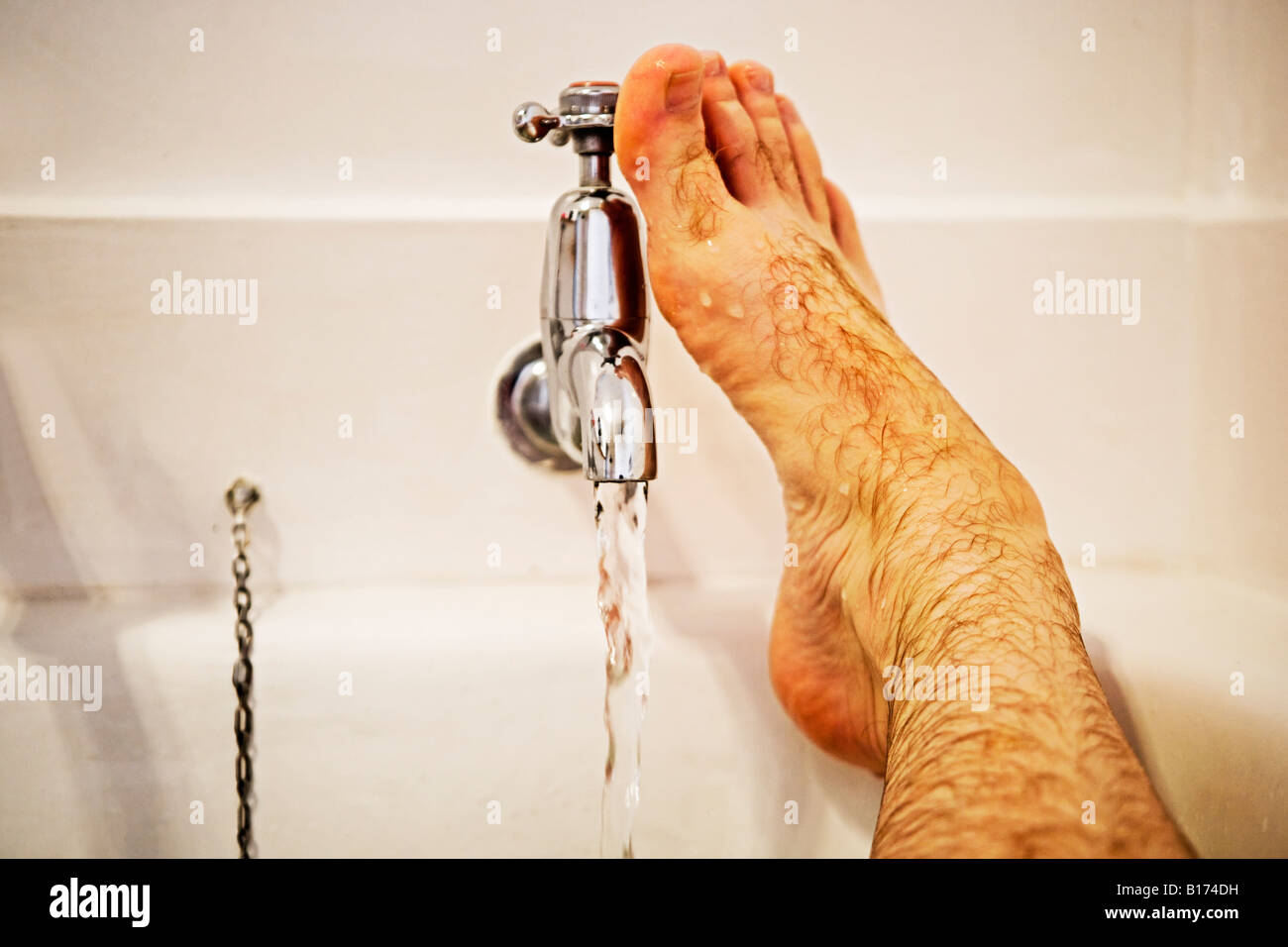 Man's foot in bath turns on tap Stock Photo