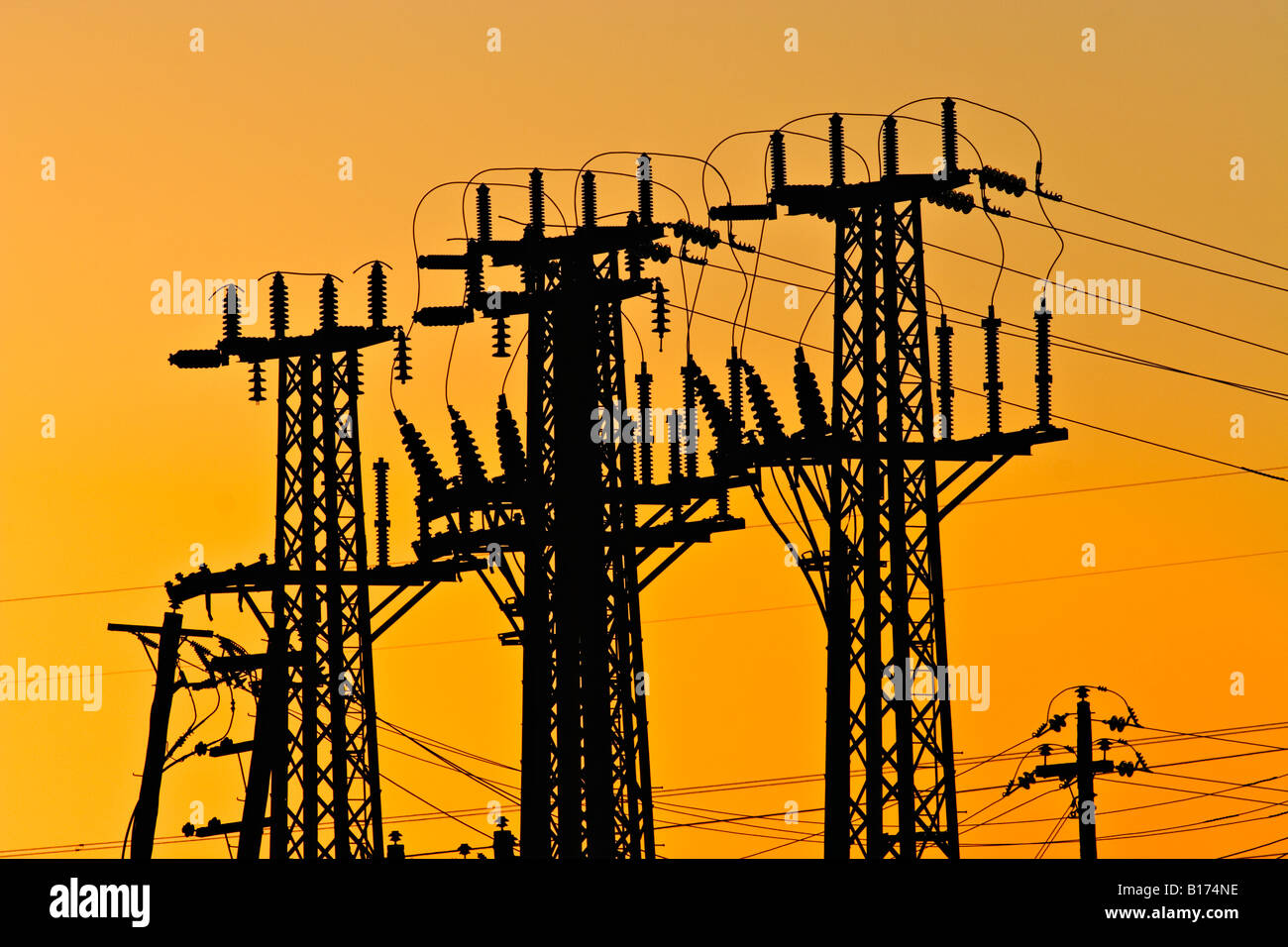 Energy Industry / Electricity. High voltage Transmission Towers silhouetted at sunset. Stock Photo