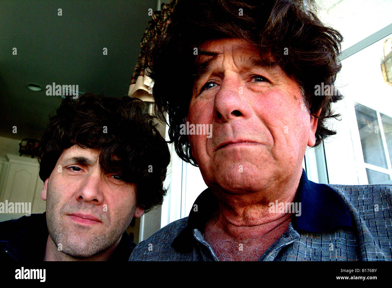 Younger man and an elderly man wearing  badly fitted wigs Stock Photo