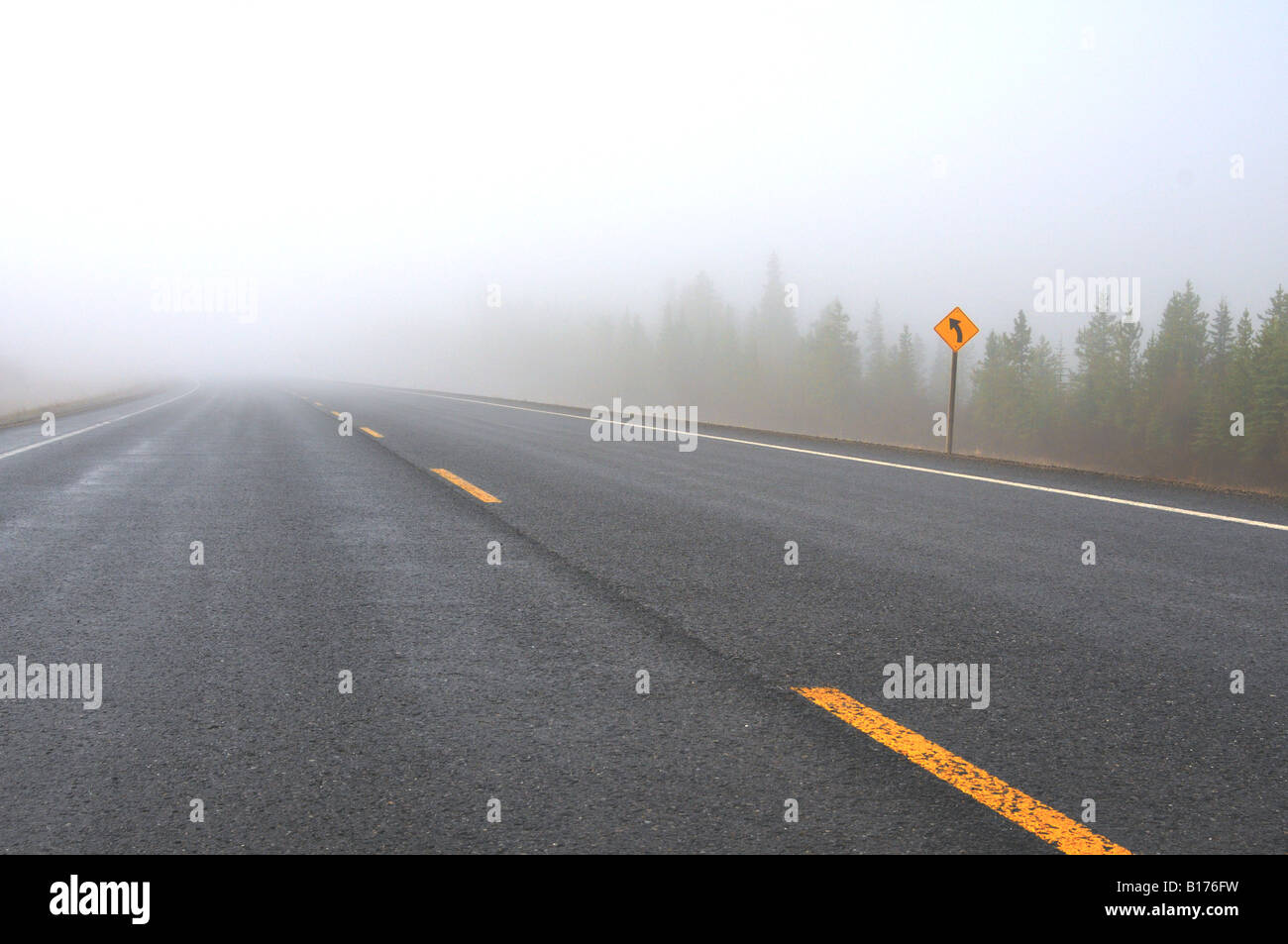 A two lane highway fading into the fog Stock Photo