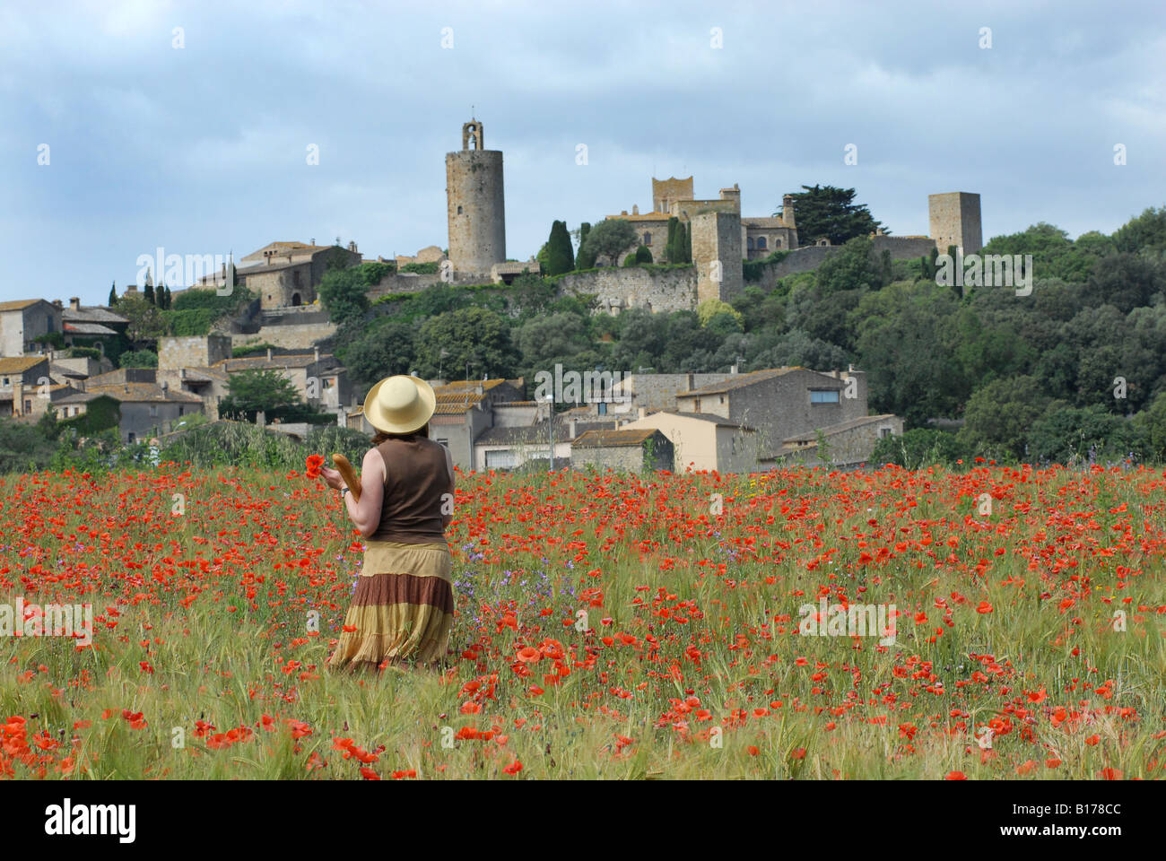 Lady walking through field of wild flowers carrying a baguette near Pals in Spain Stock Photo