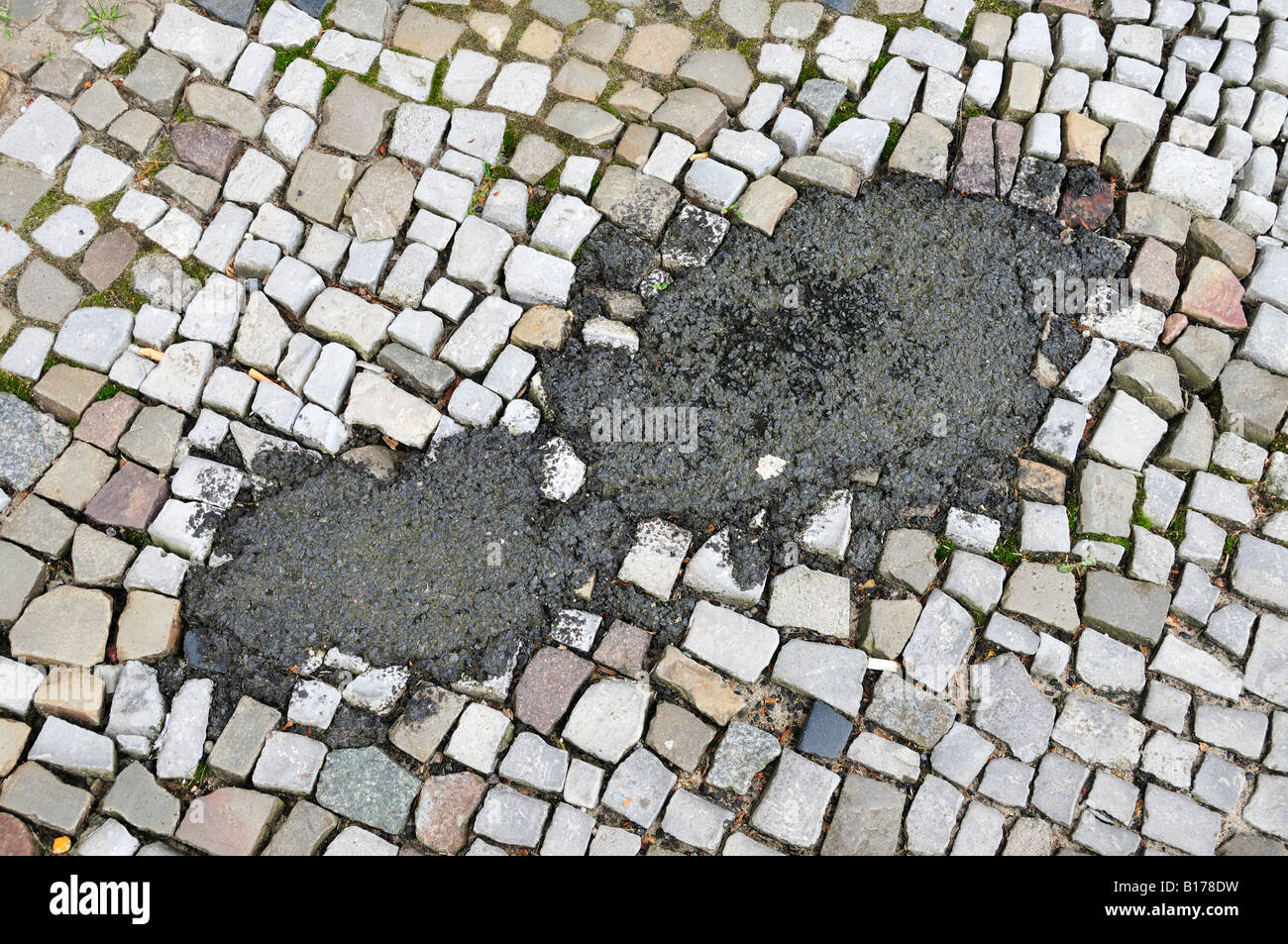 Cobblestone pavement repaired with asphalt Stock Photo - Alamy