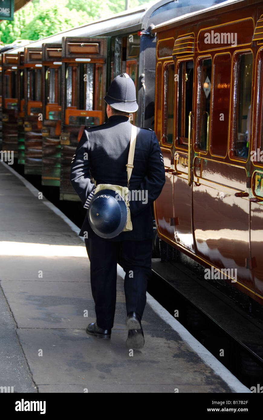 World war two time Bobby walking down steam train platform with tin hat and gas mask on his back Stock Photo