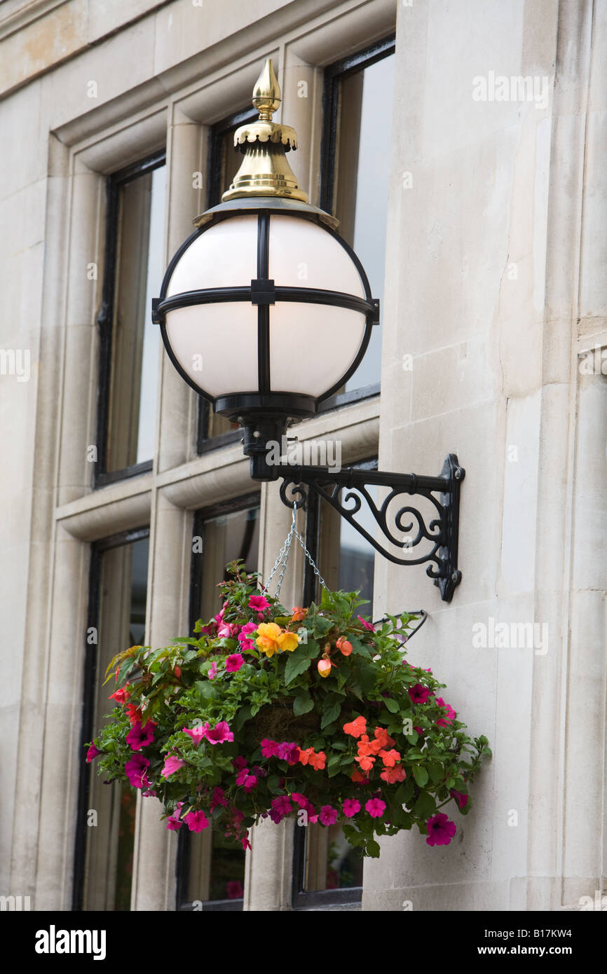 An ornate exterior light and hanging basket outside a pub in West