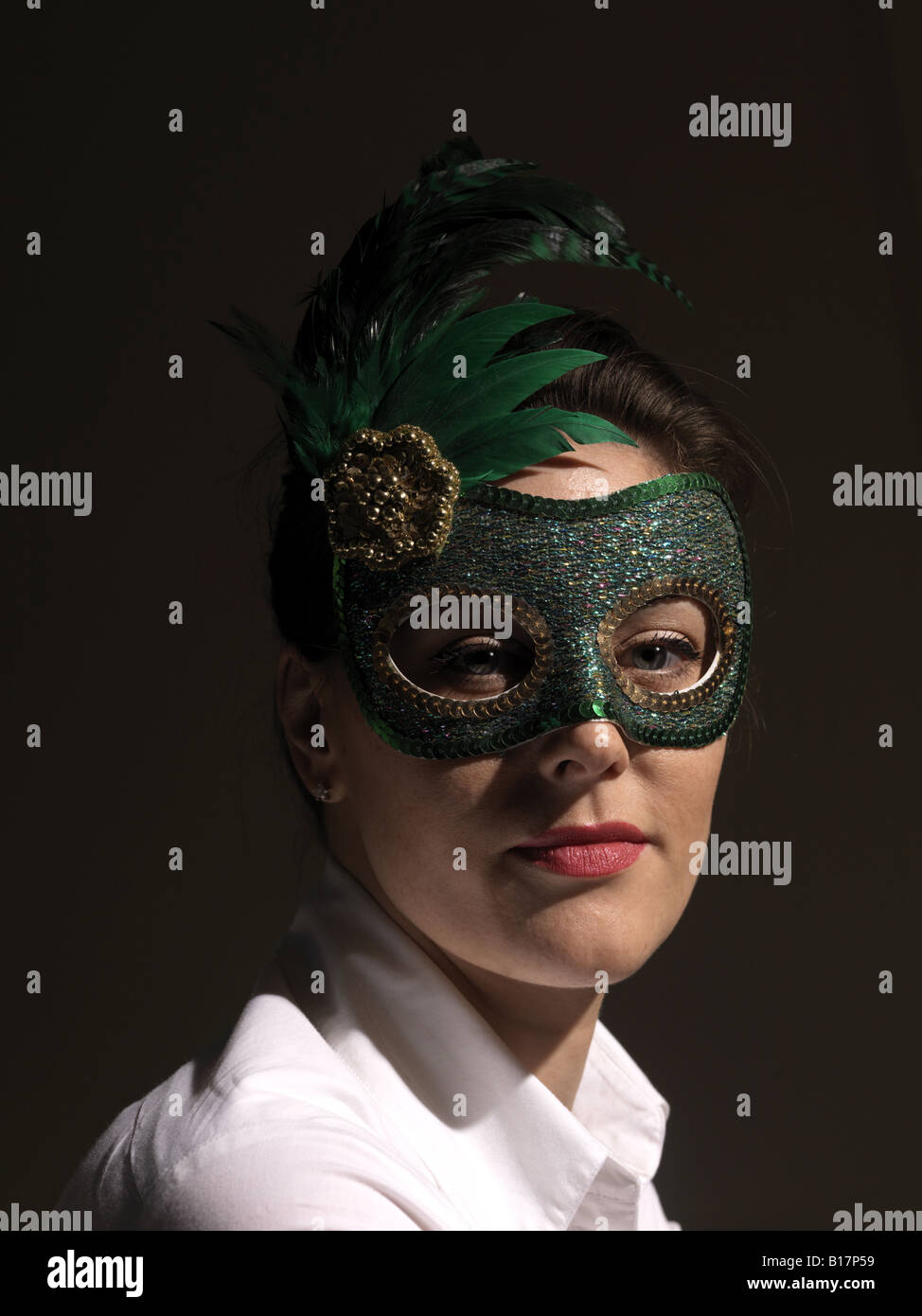 Enigmatic young woman in green mask against black background Stock Photo