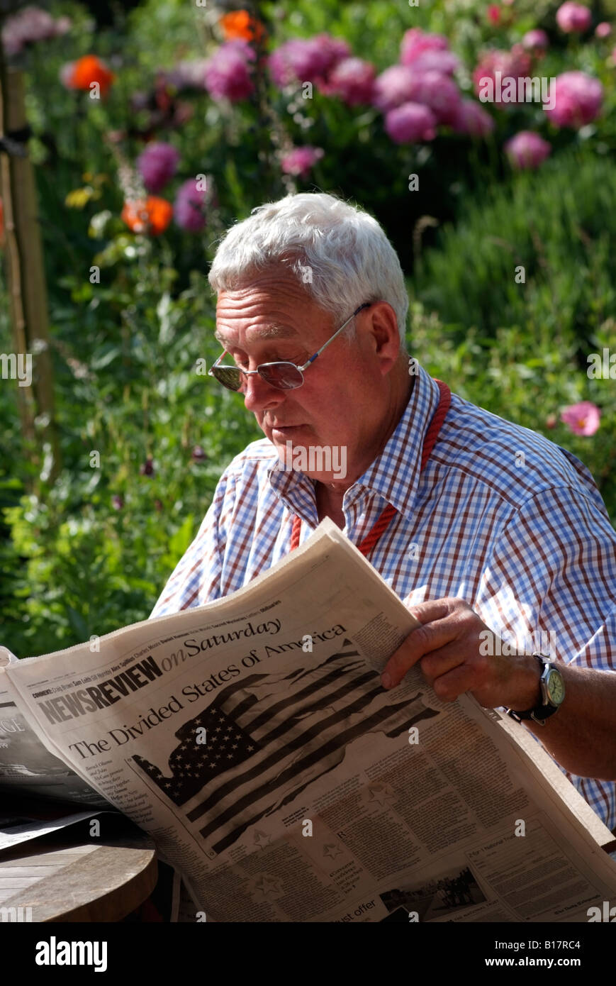 Man reading a newspaper sitting in garden Stock Photo Alamy