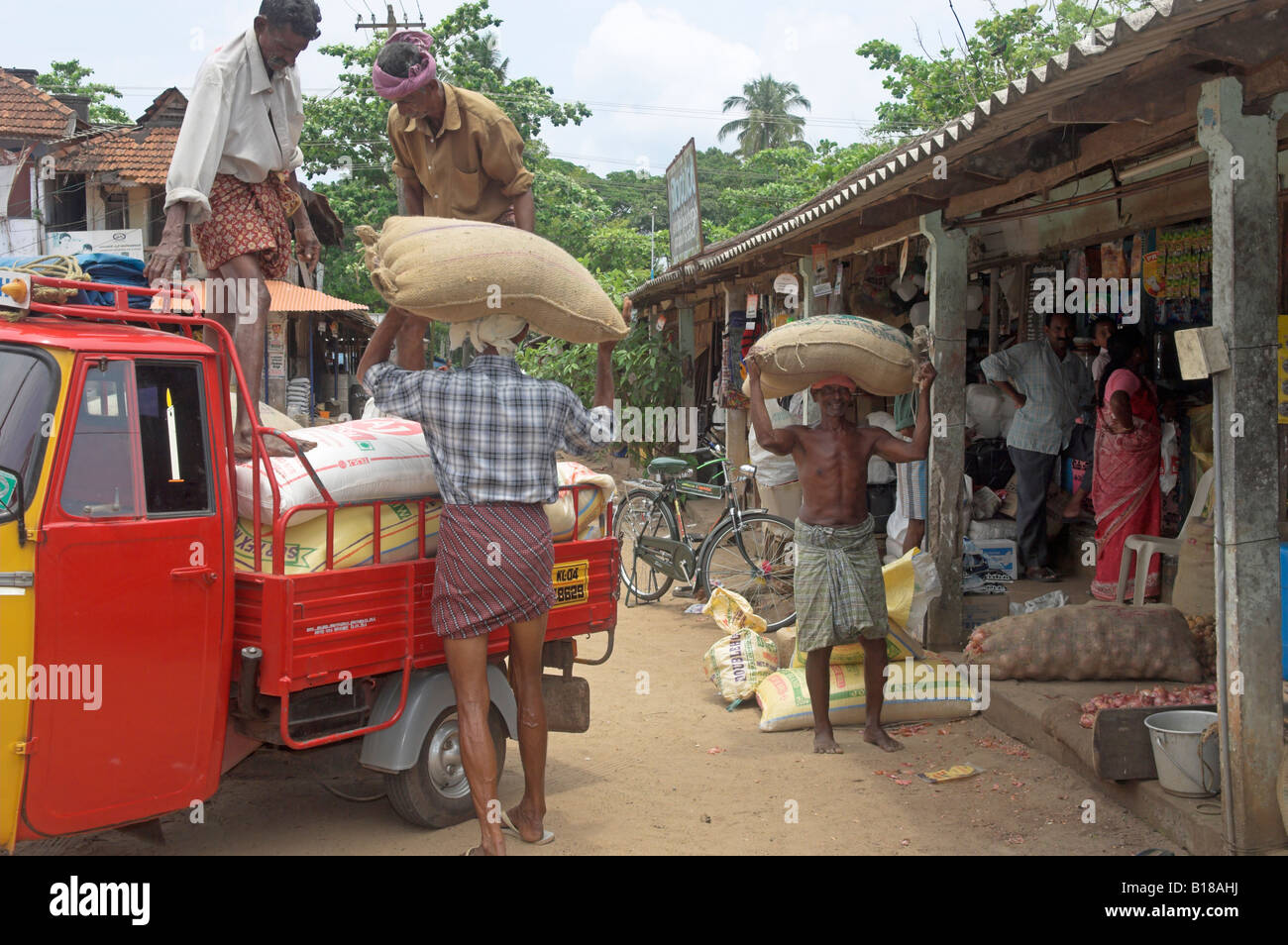 Local shopping area with bags of rice being unloaded from tuc tuc truck into market Stock Photo