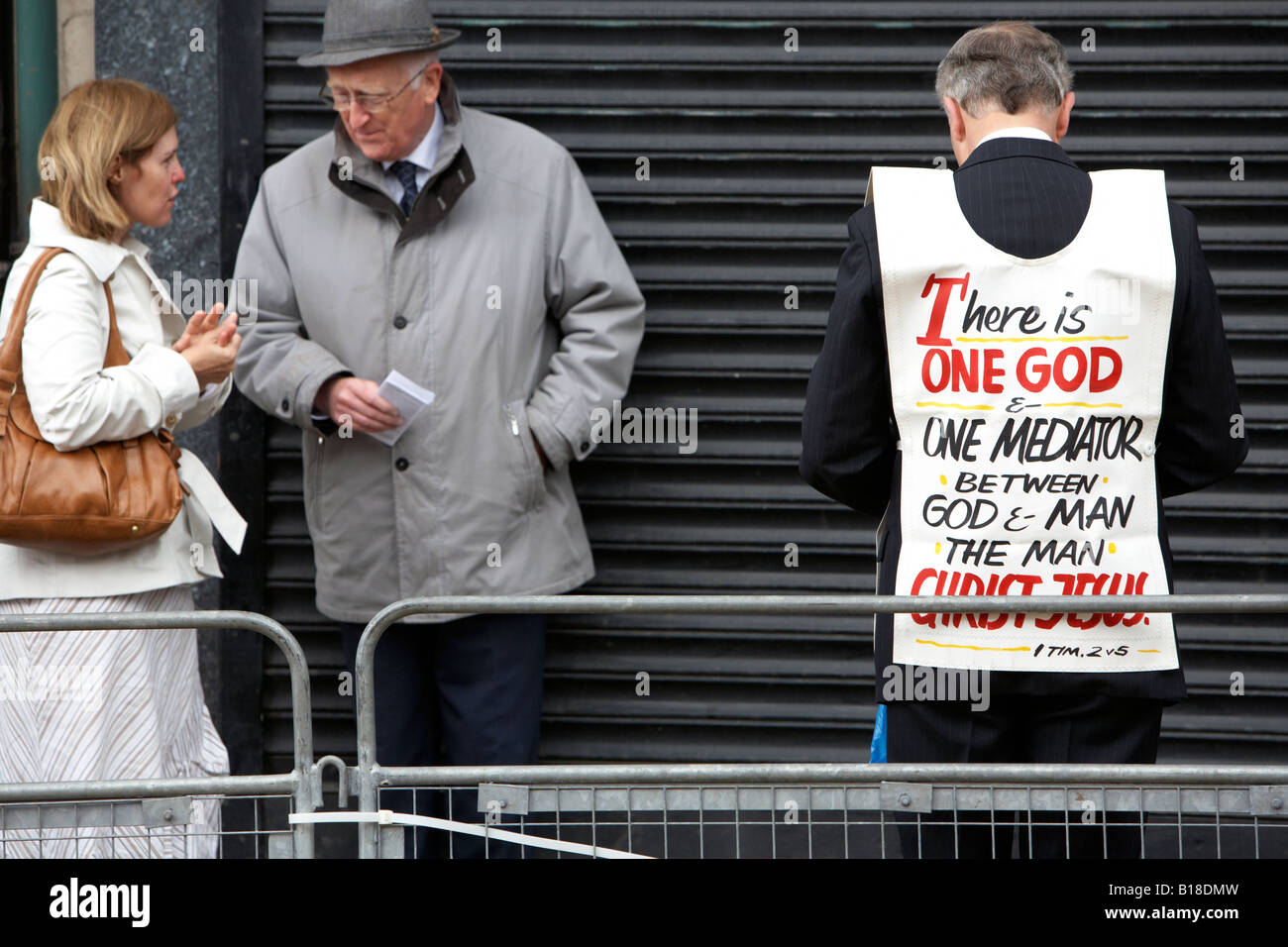 christian religious fundamentalists talking to woman in street in front of closed shop Stock Photo