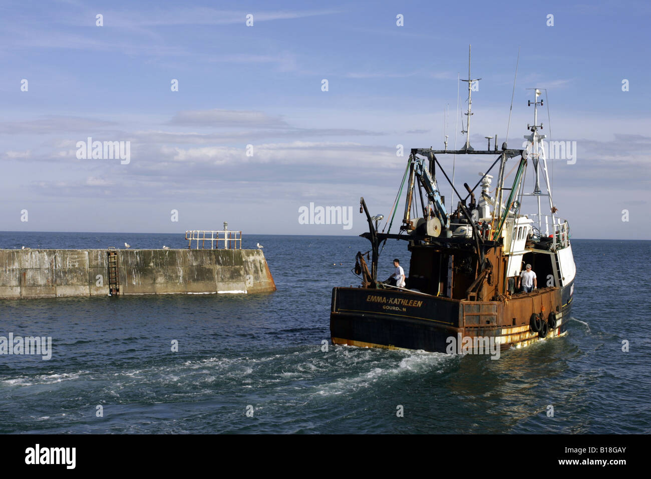 Fishing boat leaves the harbour at the small coastal village of Gourdon, Aberdeenshire, Scotland, UK Stock Photo