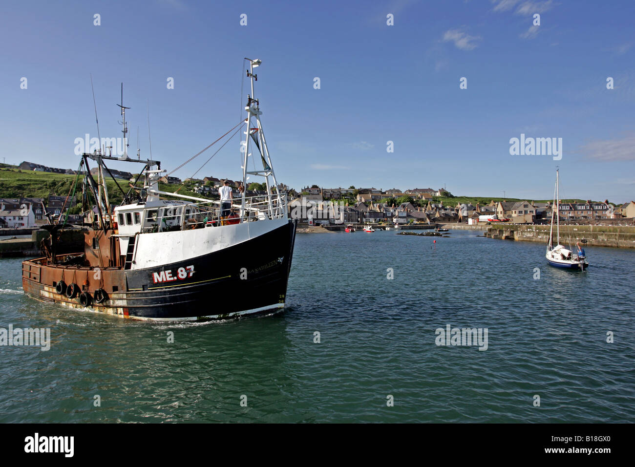 Fishing boat leaves the harbour at the small coastal village of Gourdon, Aberdeenshire, Scotland, UK Stock Photo