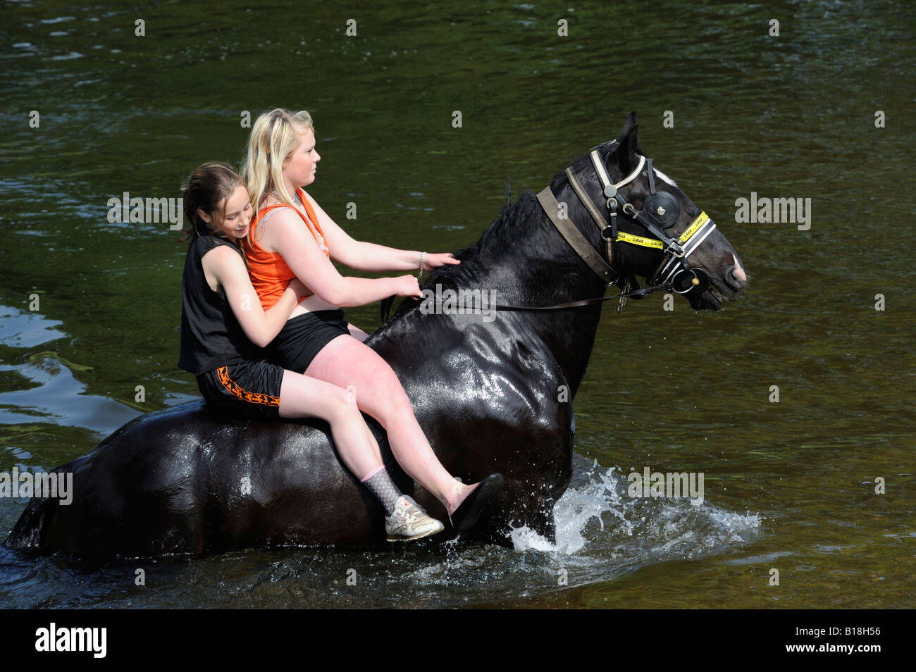 Two gypsy traveller girls riding a horse in the River Eden. Appleby Horse Fair. Appleby-in-Westmorland, Cumbria, England. Stock Photo