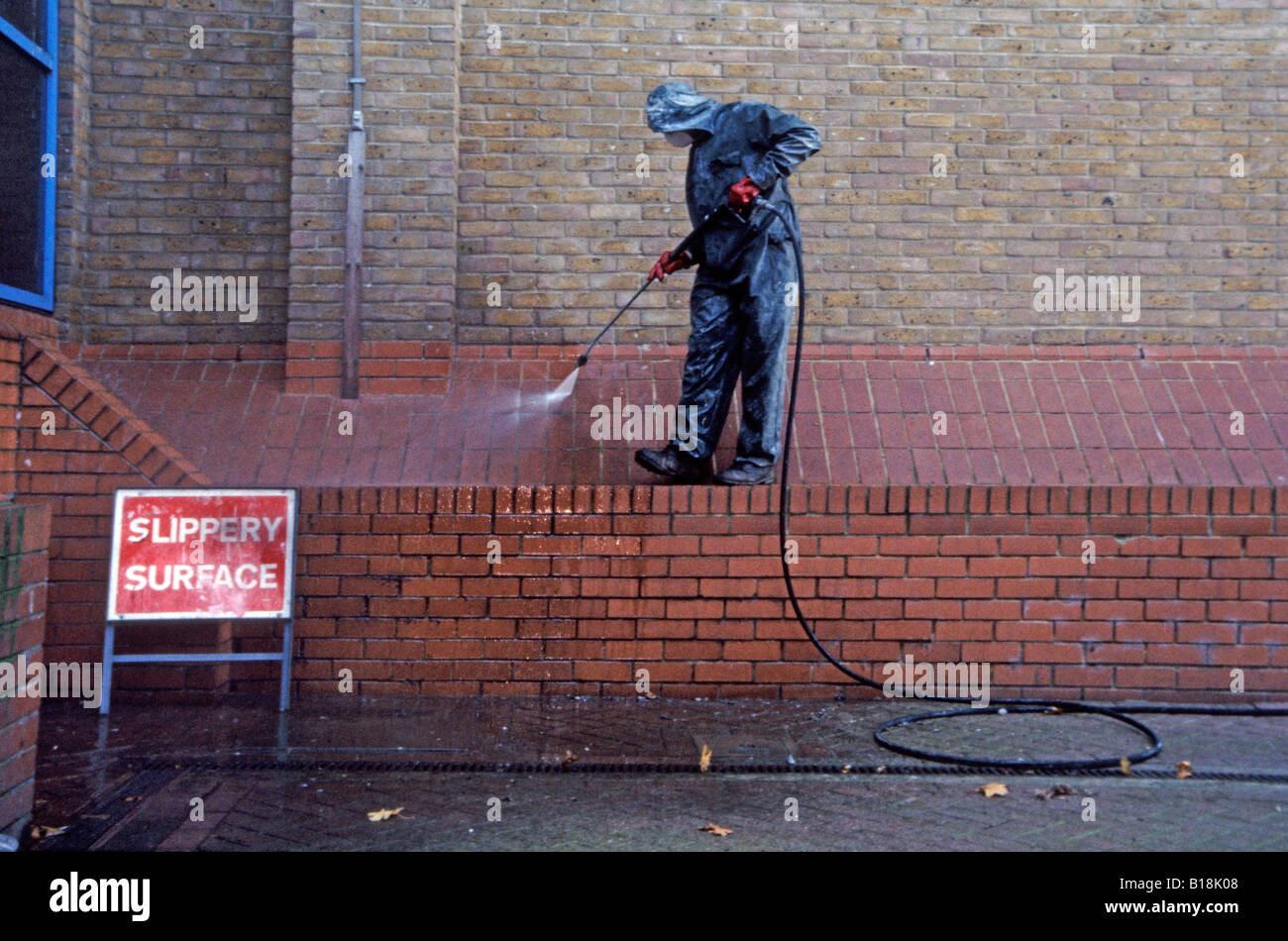 Council worker spray cleaning pigeon droppings from building in Greenwich, London, England, UK Stock Photo