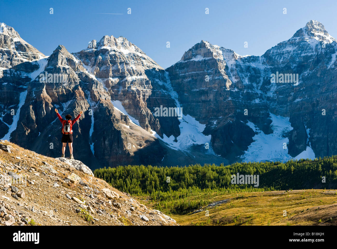 A female hiker looks out over Larch Valley on the trail to Sentinel Pass near Moraine Lake, Banff National Park, Alberta, Canada Stock Photo