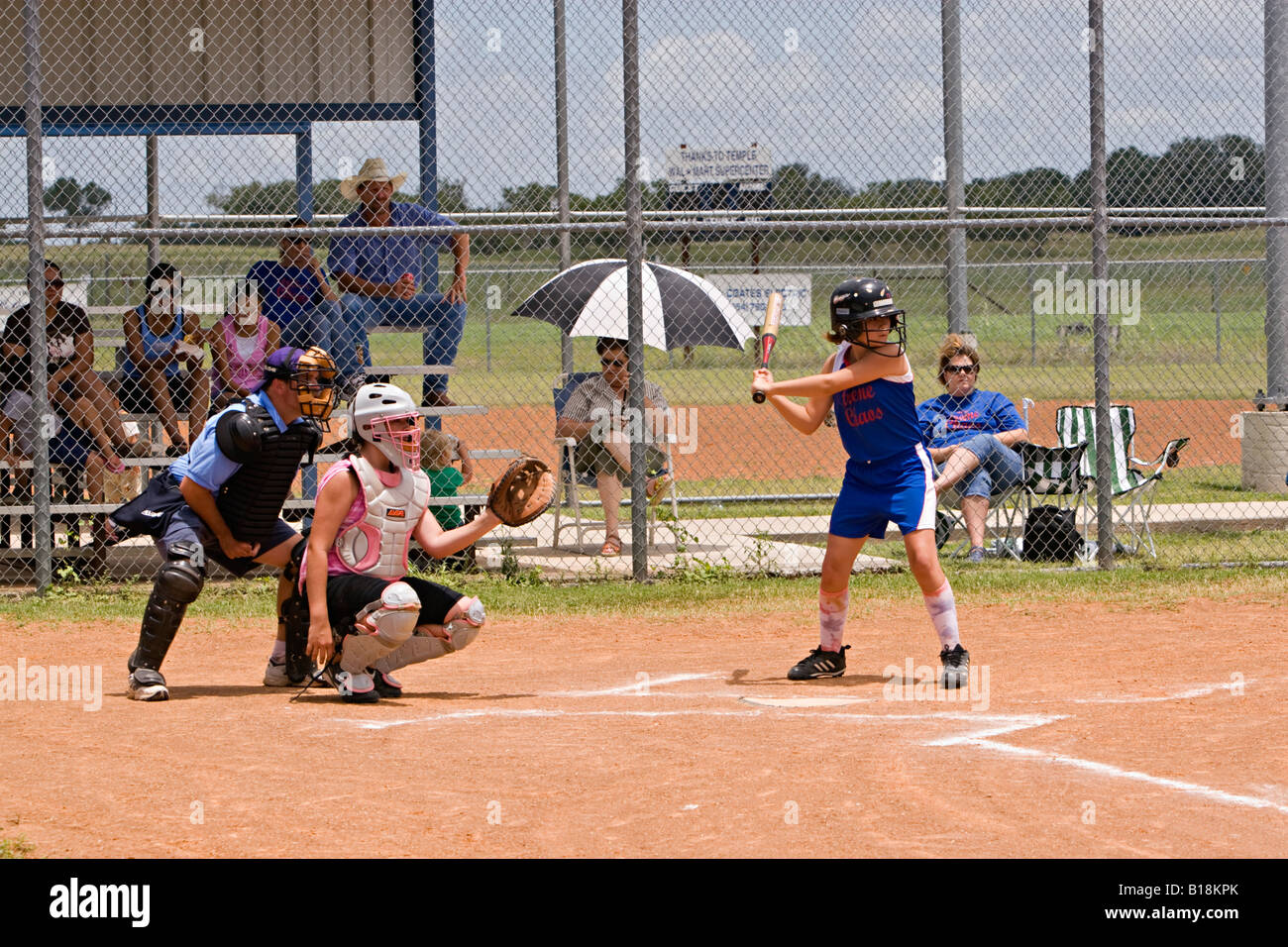 Girls youth softball team batter waiting for pitch with catcher and
