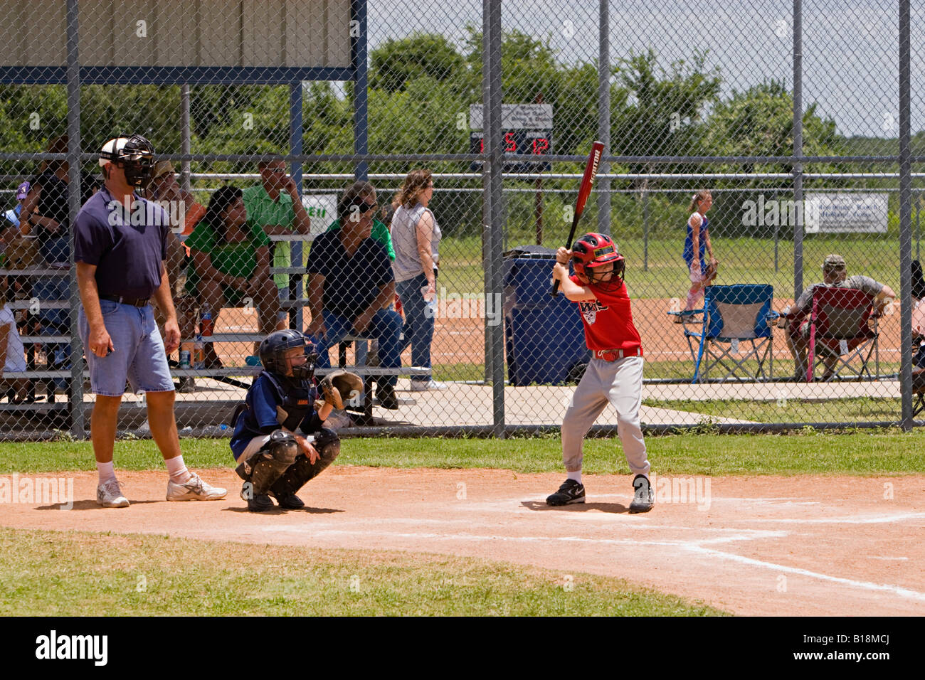 Youth softball batter waiting on pitch with catcher and game umpire at