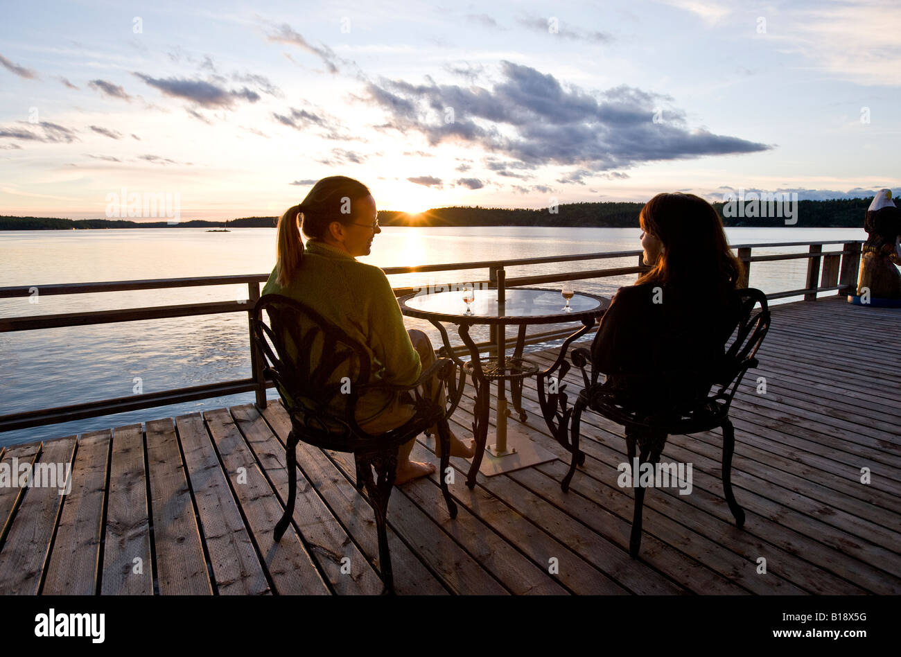 Two women enjoy aperitifs at cottage (camp) at Clearwater Bay, Lake of the Woods, Ontario, Canada. Stock Photo