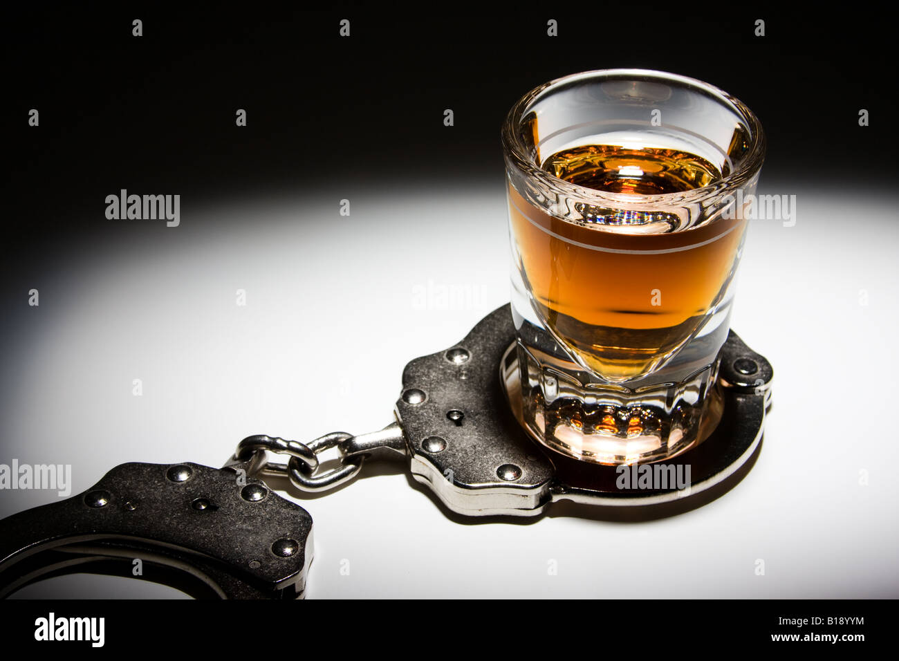 Shot Glass with Liquor and Handcuffs, White Background, Spotlight Stock