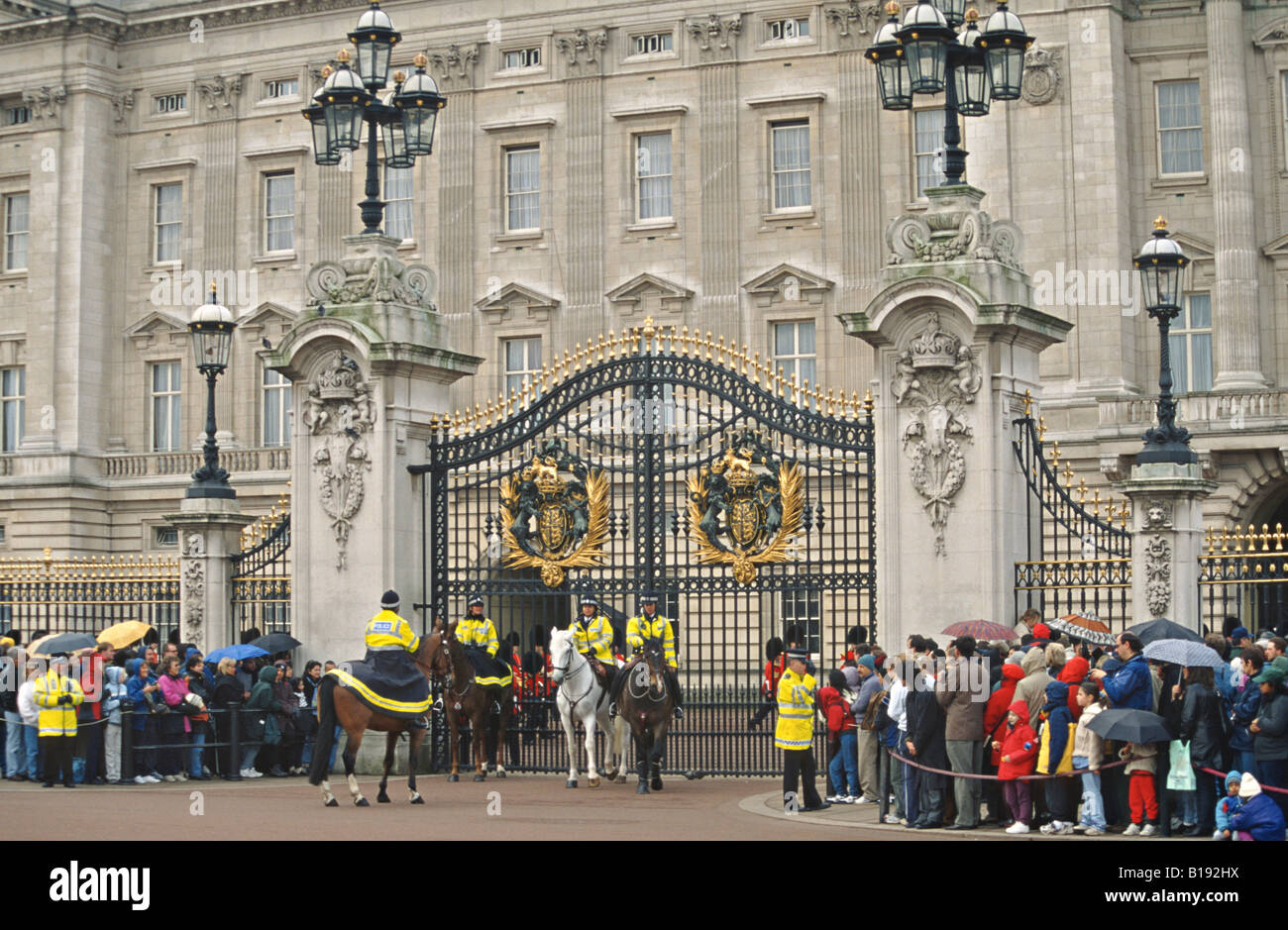 GREAT BRITAIN London Crowds line sidewalk foot mounted police by gates Buckingham Palace wait for changing guard ceremony Stock Photo