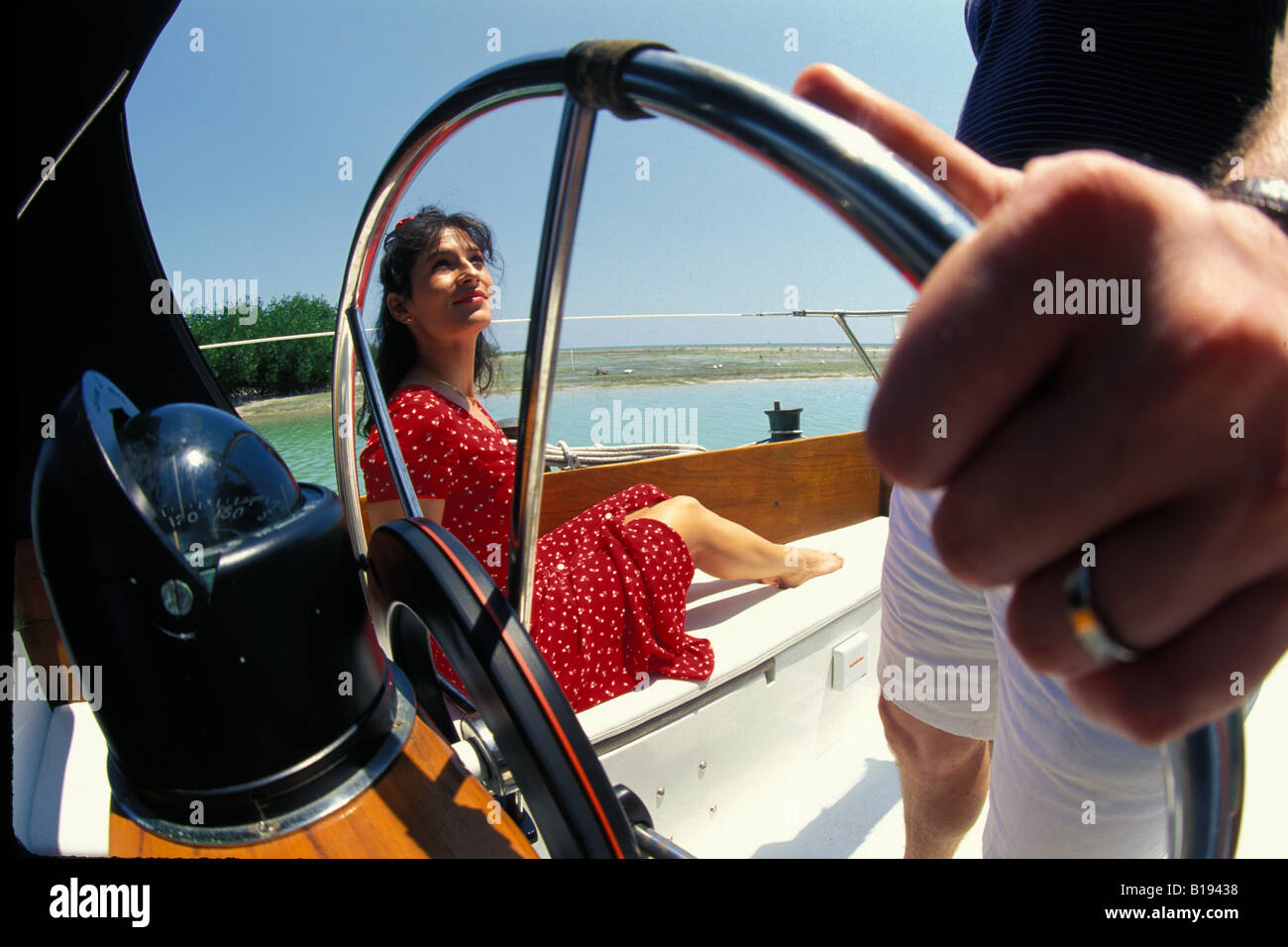 A pretty brunette woman in a red dress enjoys a summer boat ride in the ...