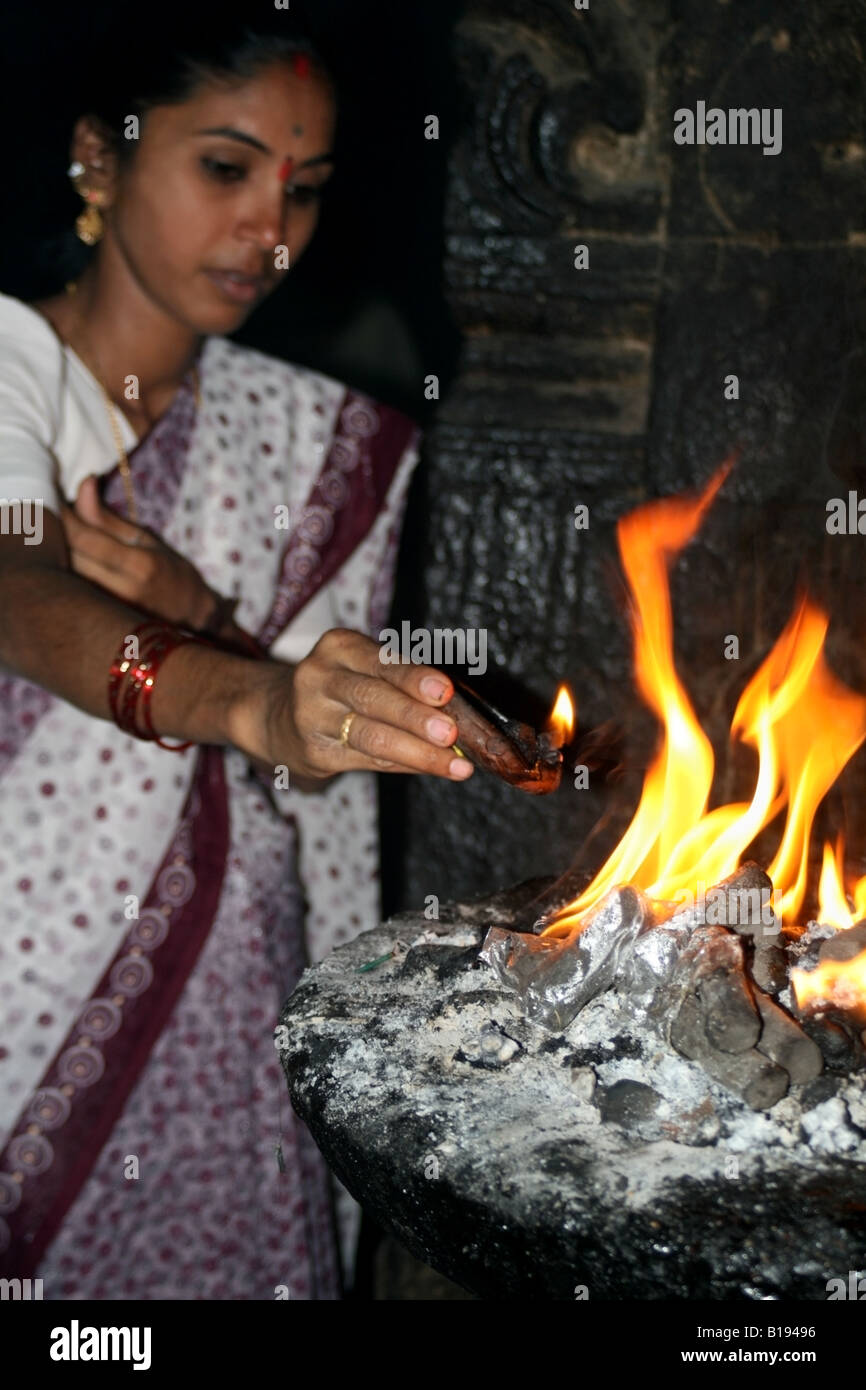 Hindu woman placing arti pooja into an old havan at a Shiva temple in