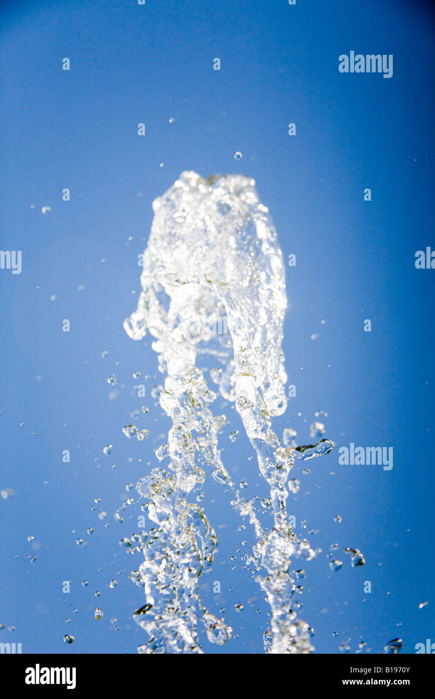 Jet of water frozen against a bright blue sky. Stock Photo