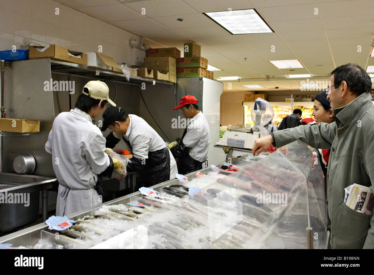 MASSACHUSETTS Boston Chinatown district in city woman and man purchase fish interior of grocery