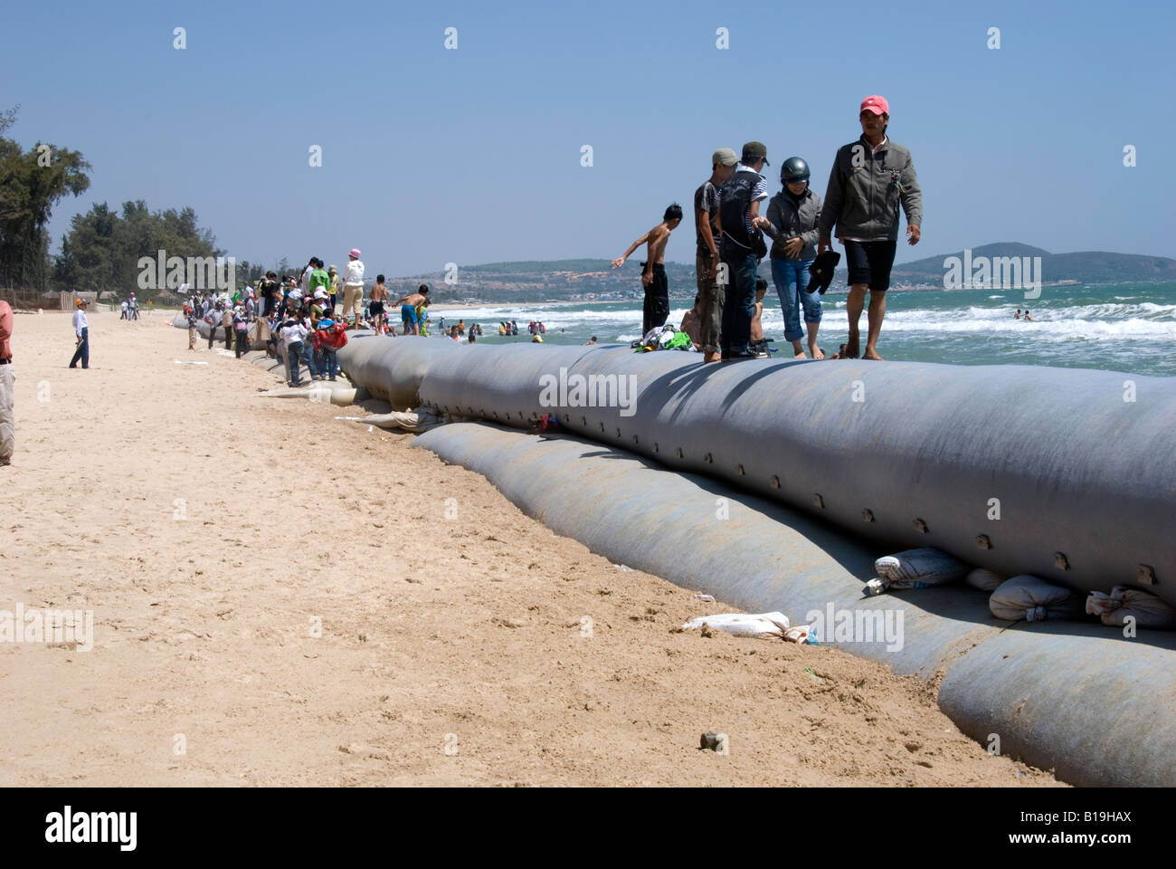 People relax by walking along the huge sandbags put in place to protect the remaining beach area from further erosion Stock Photo Alamy