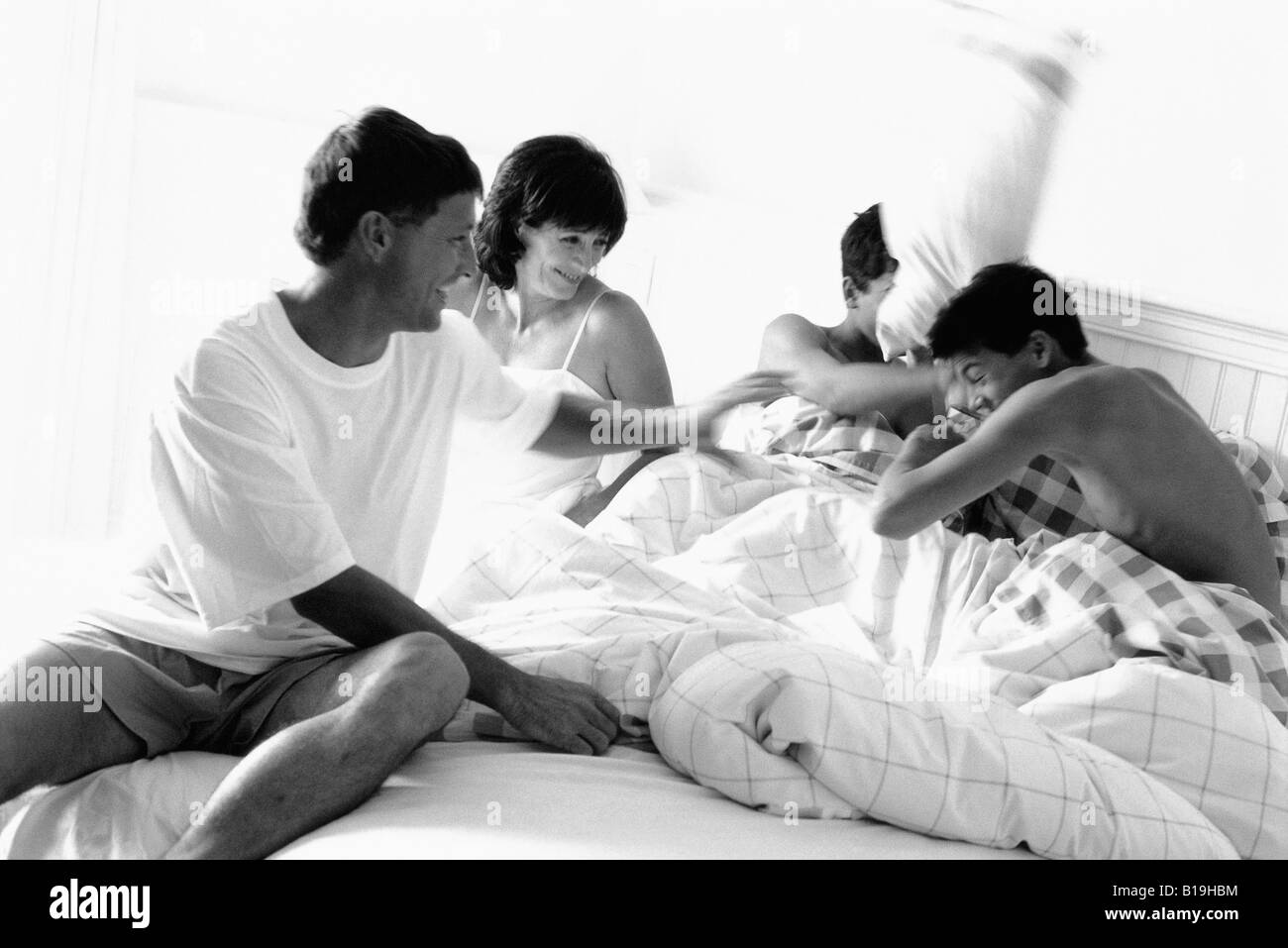 Family having pillow fight in bed, black and white Stock Photo