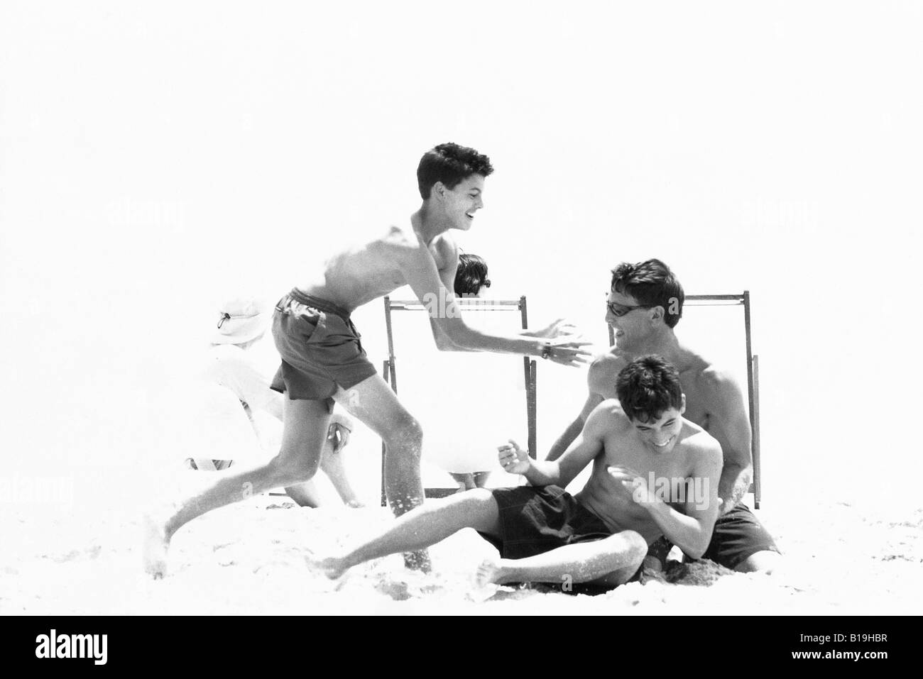 Man roughhousing on beach with teenage sons, black and white Stock Photo
