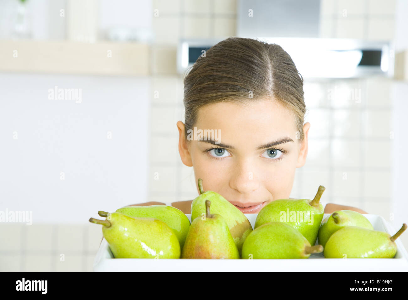 Young woman looking over tray of pears Stock Photo
