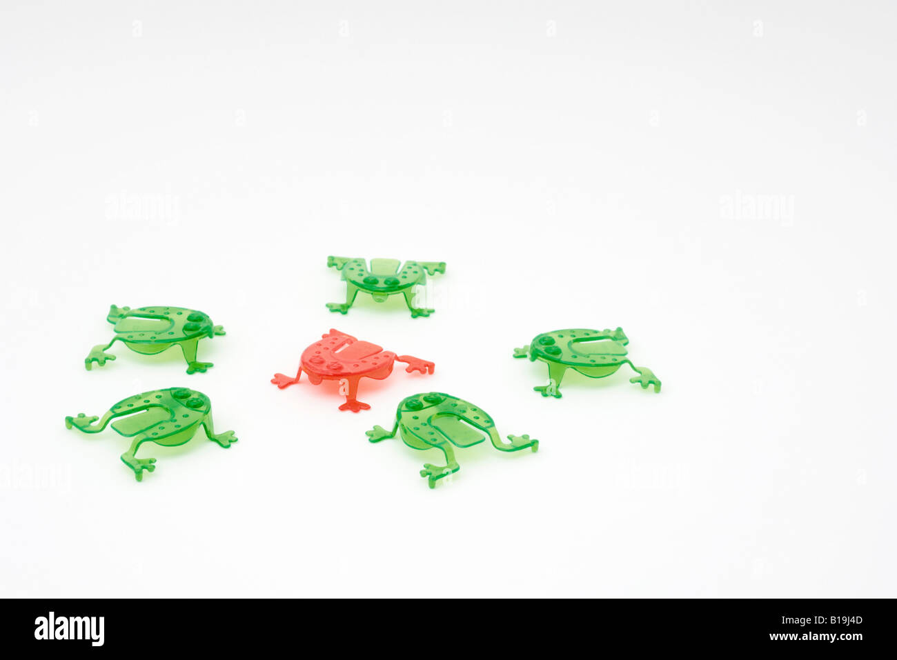 Green plastic frogs surrounding red frog in center Stock Photo Alamy