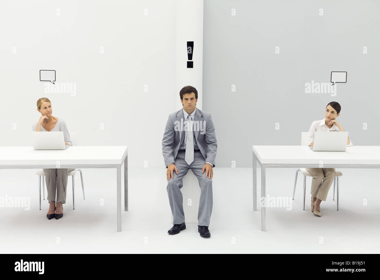 Man sitting in office with exclamation mark over his head, women on either side with blank word bubbles Stock Photo