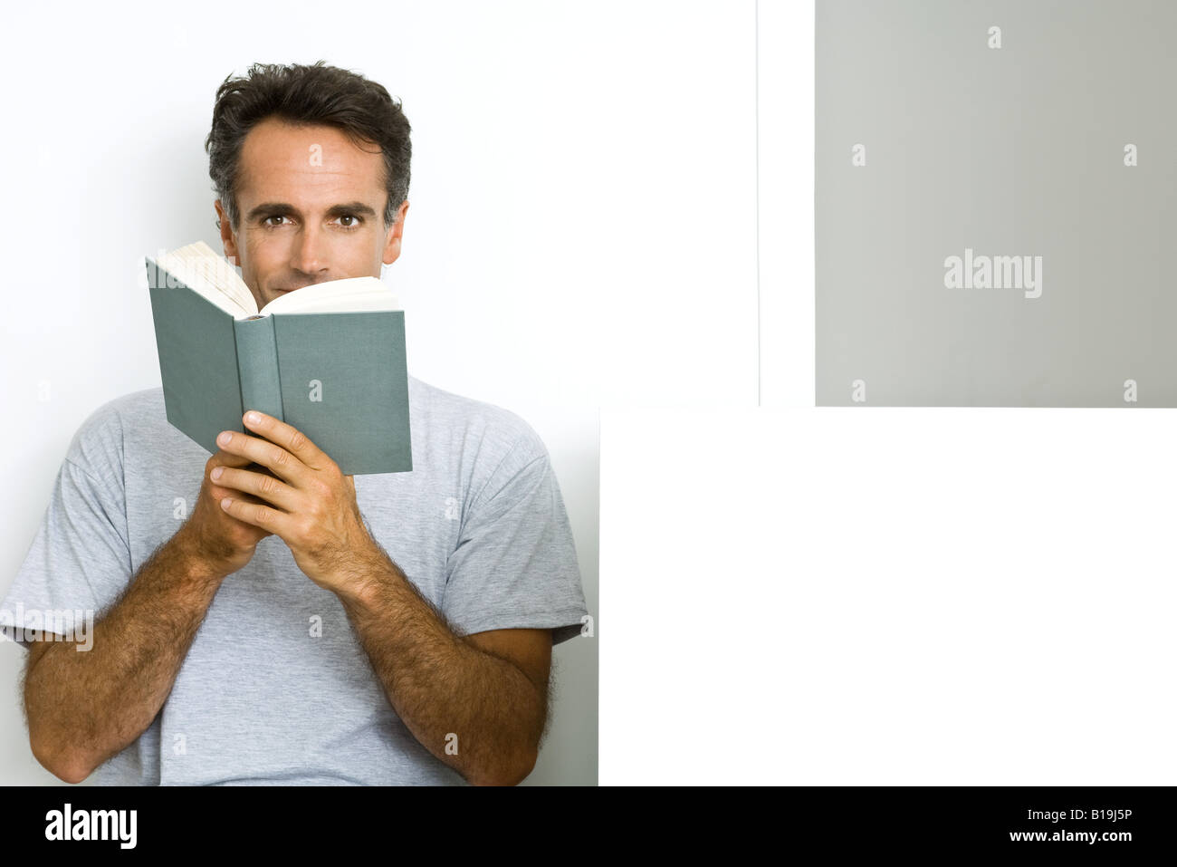 Man reading book, looking at camera Stock Photo