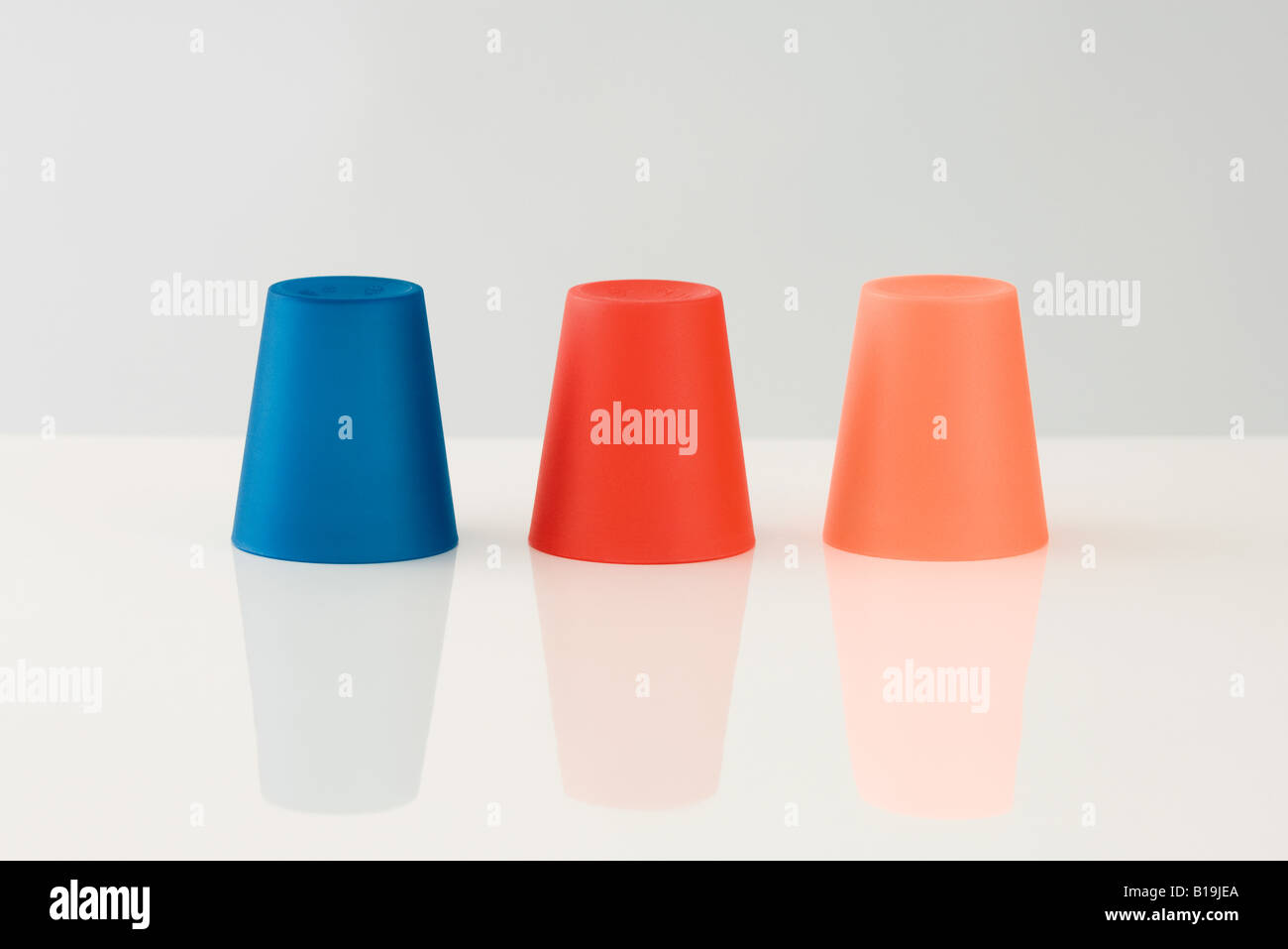 Three colored cups, upside down Stock Photo Alamy