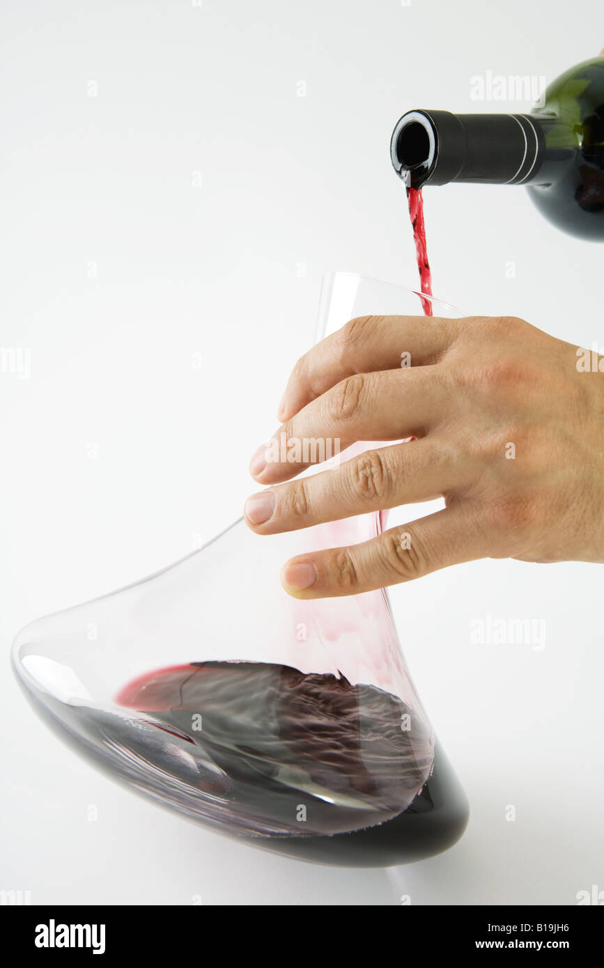 Man pouring red wine into decanter, cropped view of hand Stock Photo