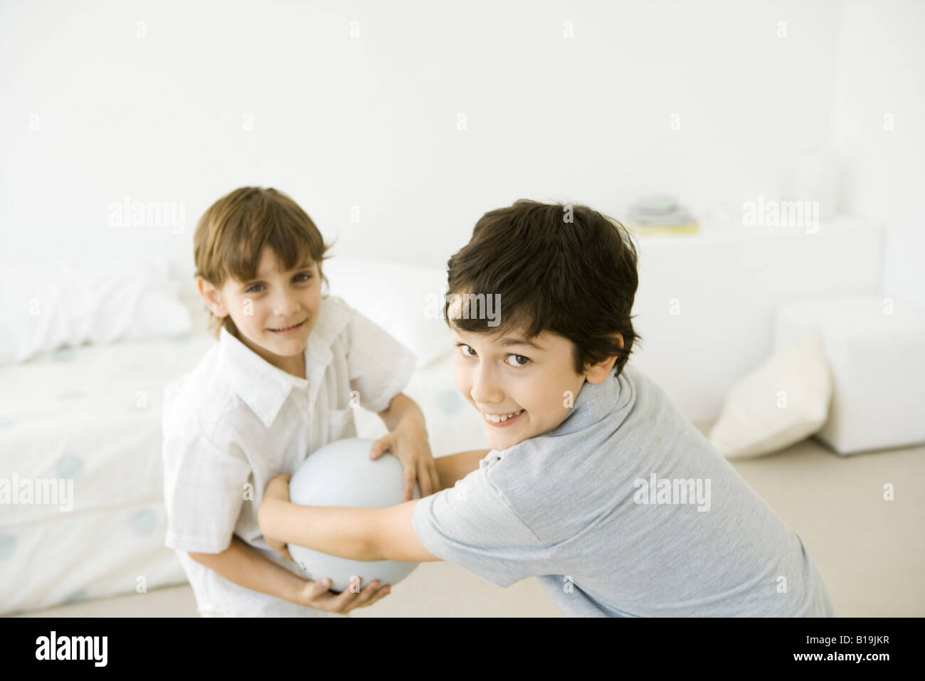 Two boys playing with ball, smiling at camera Stock Photo