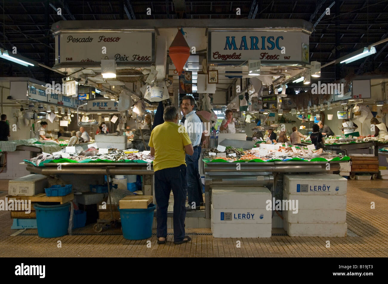 A customer at a fresh seafood stall in the fish market section of Mercat de l’Abaceria Central, Gracia, Barcelona, Spain Stock Photo