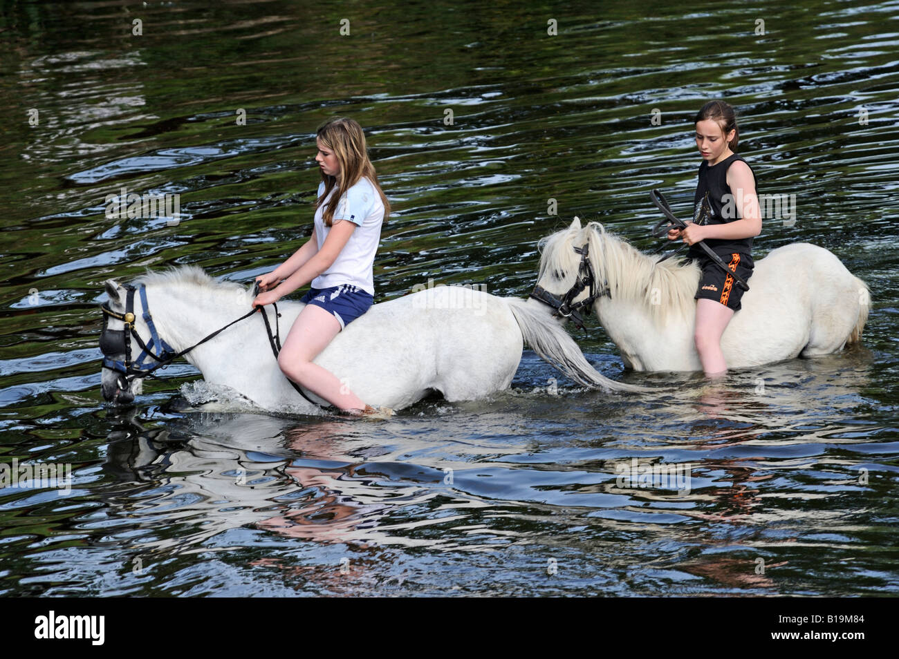 Two gypsy traveller girls riding ponies bareback in River Eden. Appleby Horse Fair. Appleby-in-Westmorland, Cumbria, England. Stock Photo