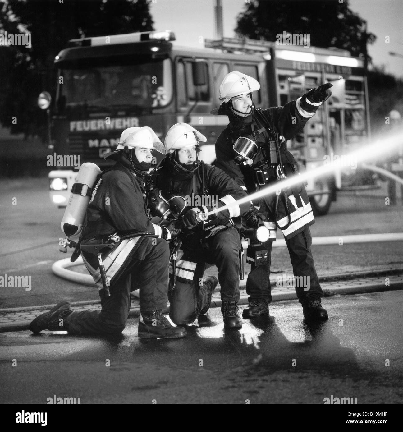 young firefighters with breathing protection and extinguisher in action, at night, black and white, Germany Stock Photo