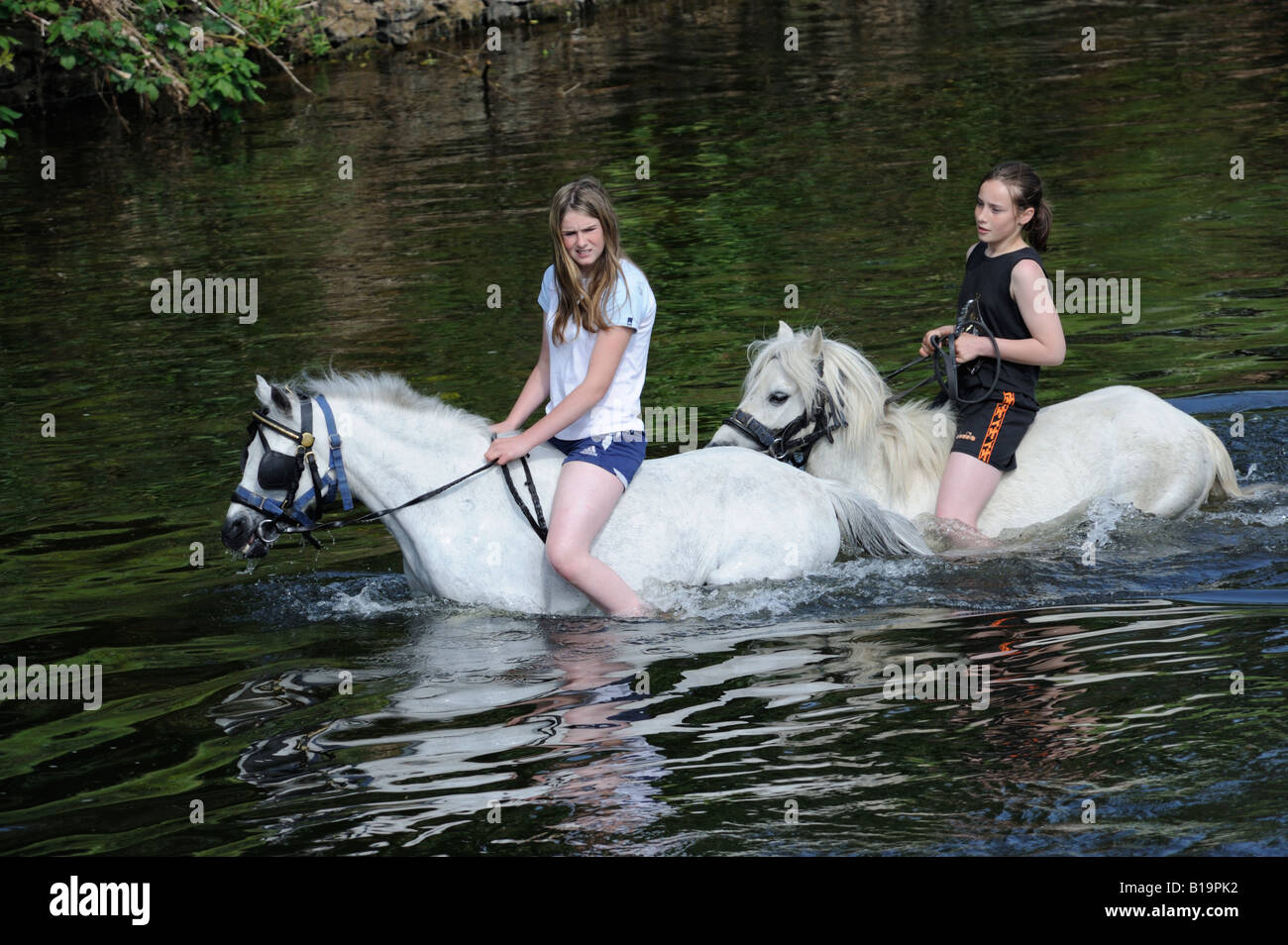 Two gypsy traveller girls riding ponies bareback in River Eden. Appleby Horse Fair. Appleby-in-Westmorland, Cumbria, England. Stock Photo
