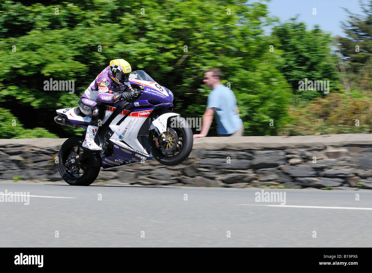 Ian Lougher lands after taking of at Sulby Bridge Superbike Race TT08. Spectator watching from behind a wall Stock Photo
