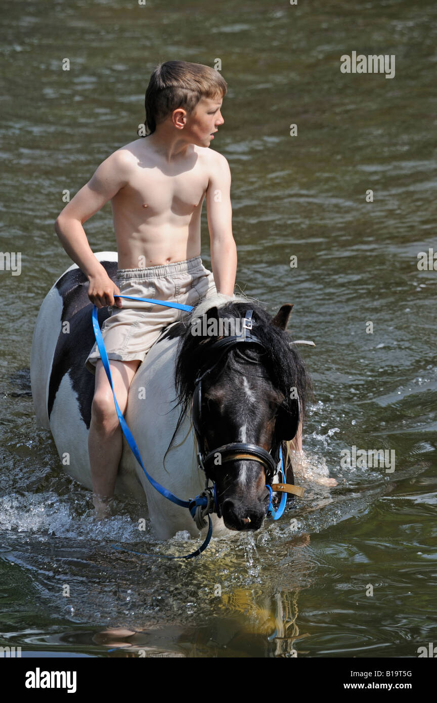 Gypsy traveller boy riding horse bareback in River Eden. Appleby Horse Fair. Appleby-in-Westmorland, Cumbria, England. Stock Photo