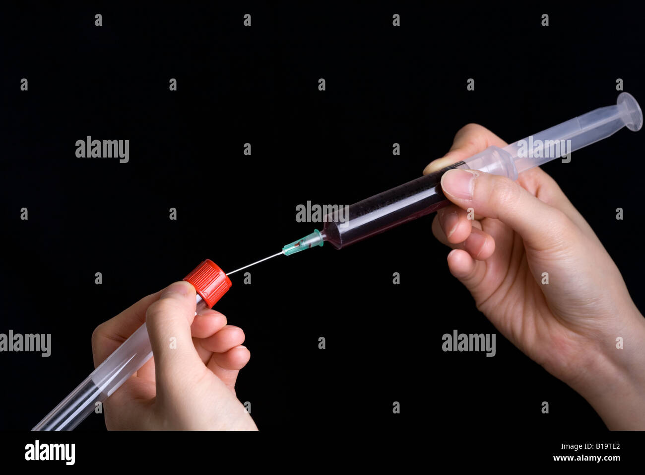 Transferring blood into a specimen container using a needle Stock Photo