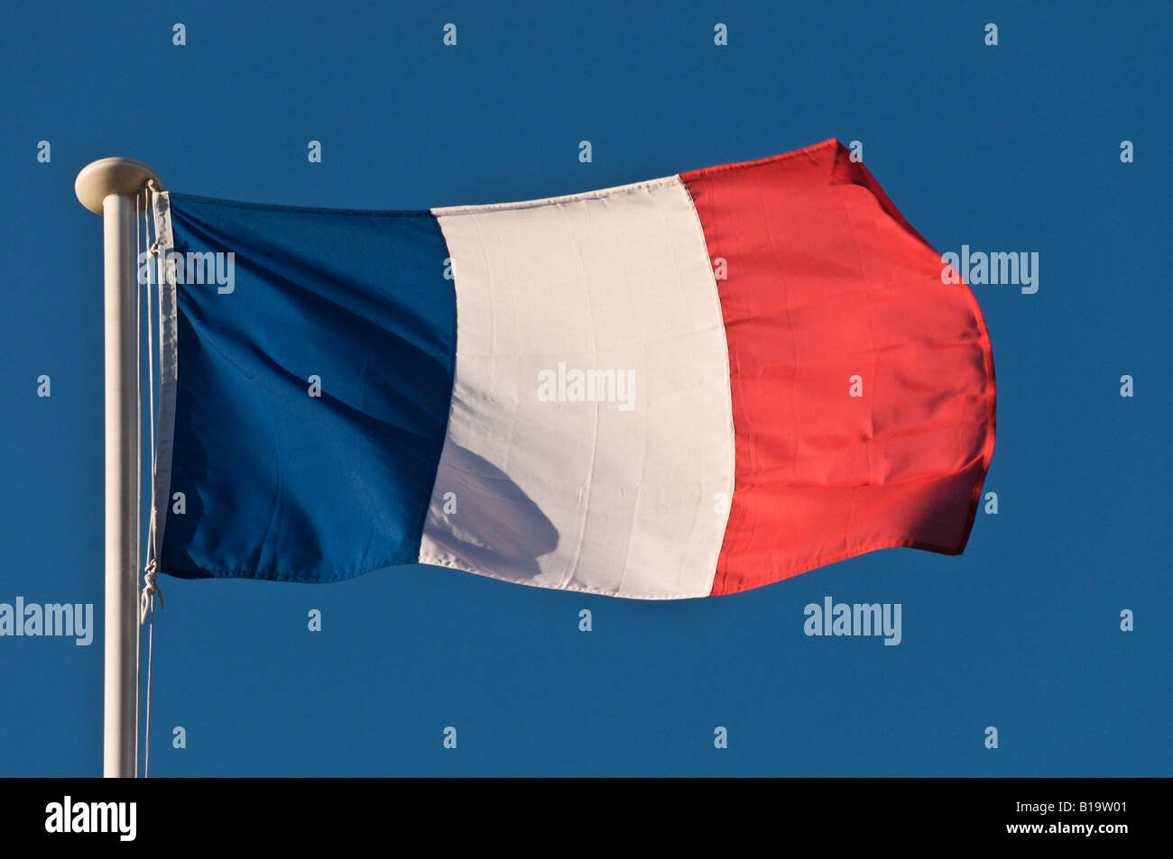 French Flag Blowing In the Wind On A Blue Sky Background. Stock Photo