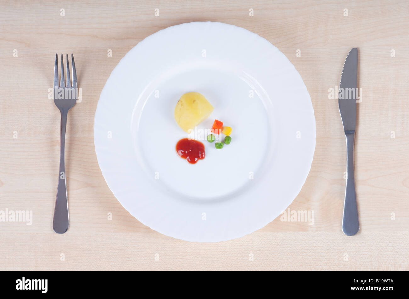 On diet: sober lunch with single potato, boiled carrot, peas, corn and tomato ketchup. Stock Photo