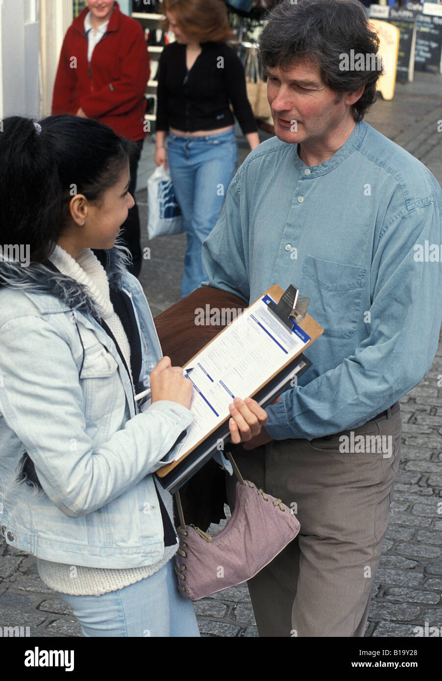 teenage girl with clipboard interviewing man on city street Stock Photo