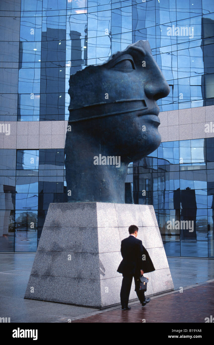 Businessman walks past modern art statue and modern building in La Defense Paris France Stock Photo